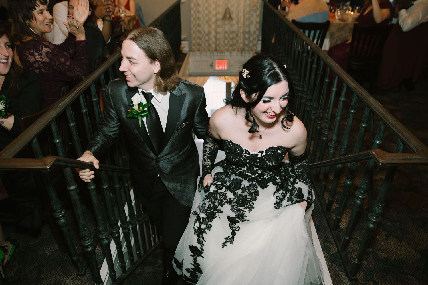 Wedding couple descends ornate staircase with the bride wearing a stunning black and white gown.