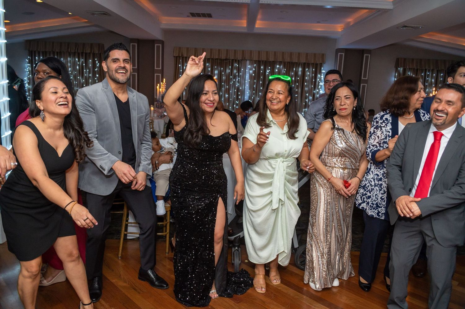 Group of party guests dancing and celebrating on dance floor at formal event.