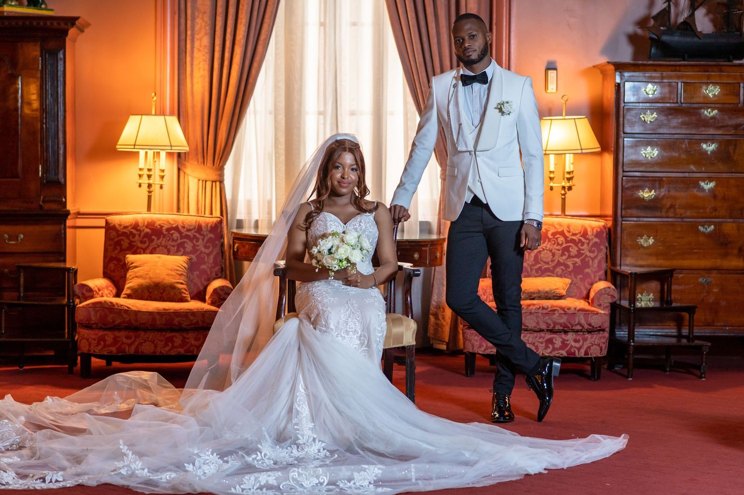 Couple in formal attire posing in elegant room with vintage furniture.