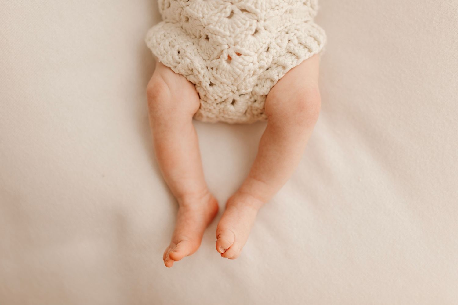 Small bare feet and legs against a white textured background.