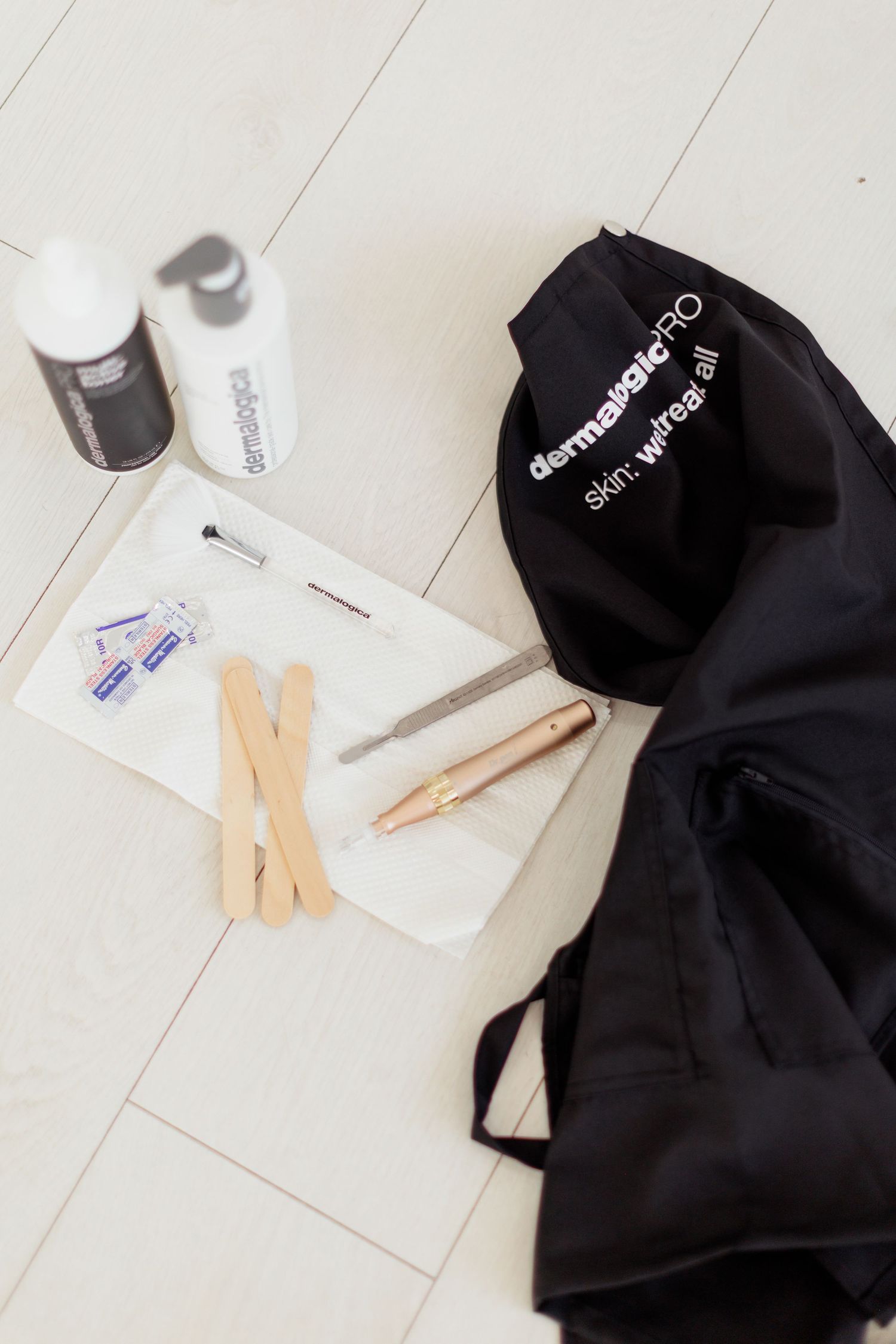 Dermalogica PRO skincare tools and products laid flat on white surface with black branded bag.