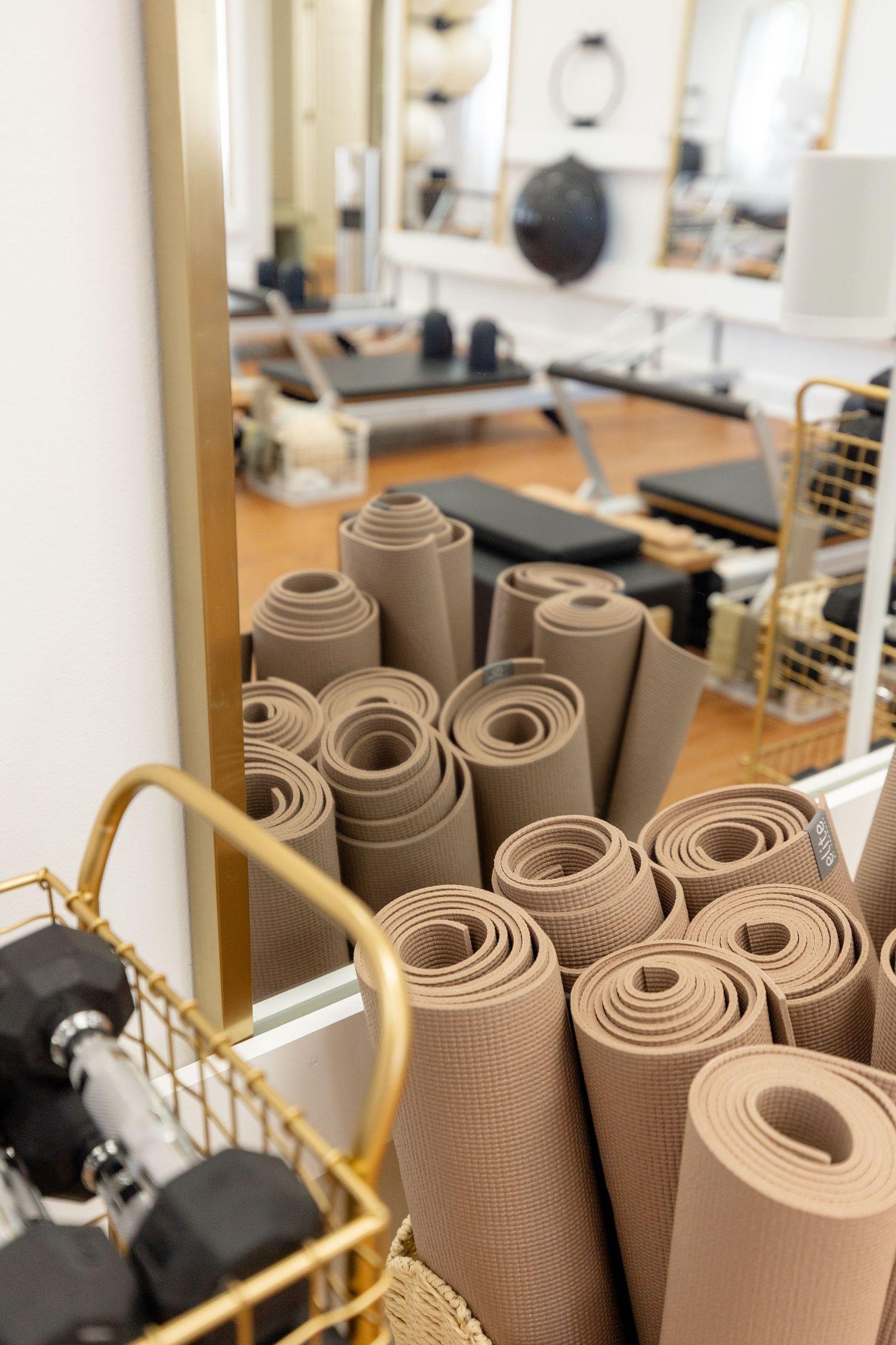Rolled up brown yoga mats stored vertically in a fitness studio.