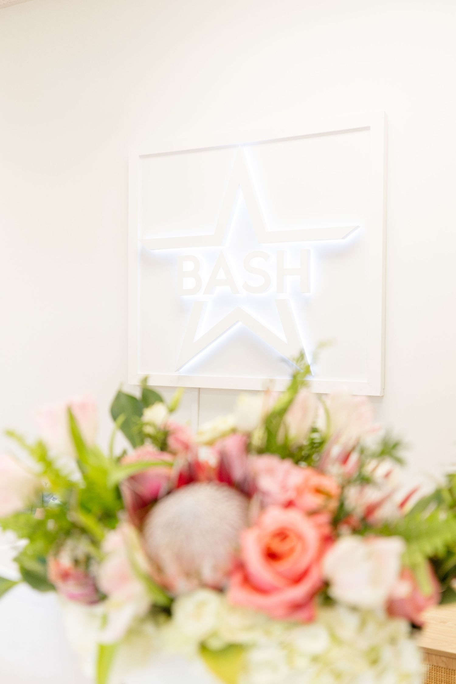 White star logo on wall with blurred pink floral arrangement in foreground.