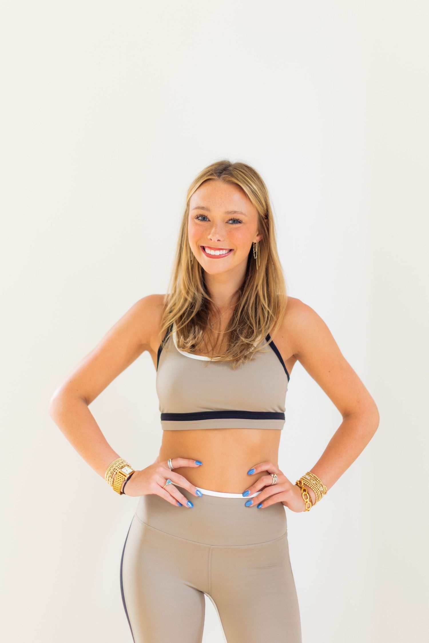 Athletic woman in grey workout attire posing with hands on hips.