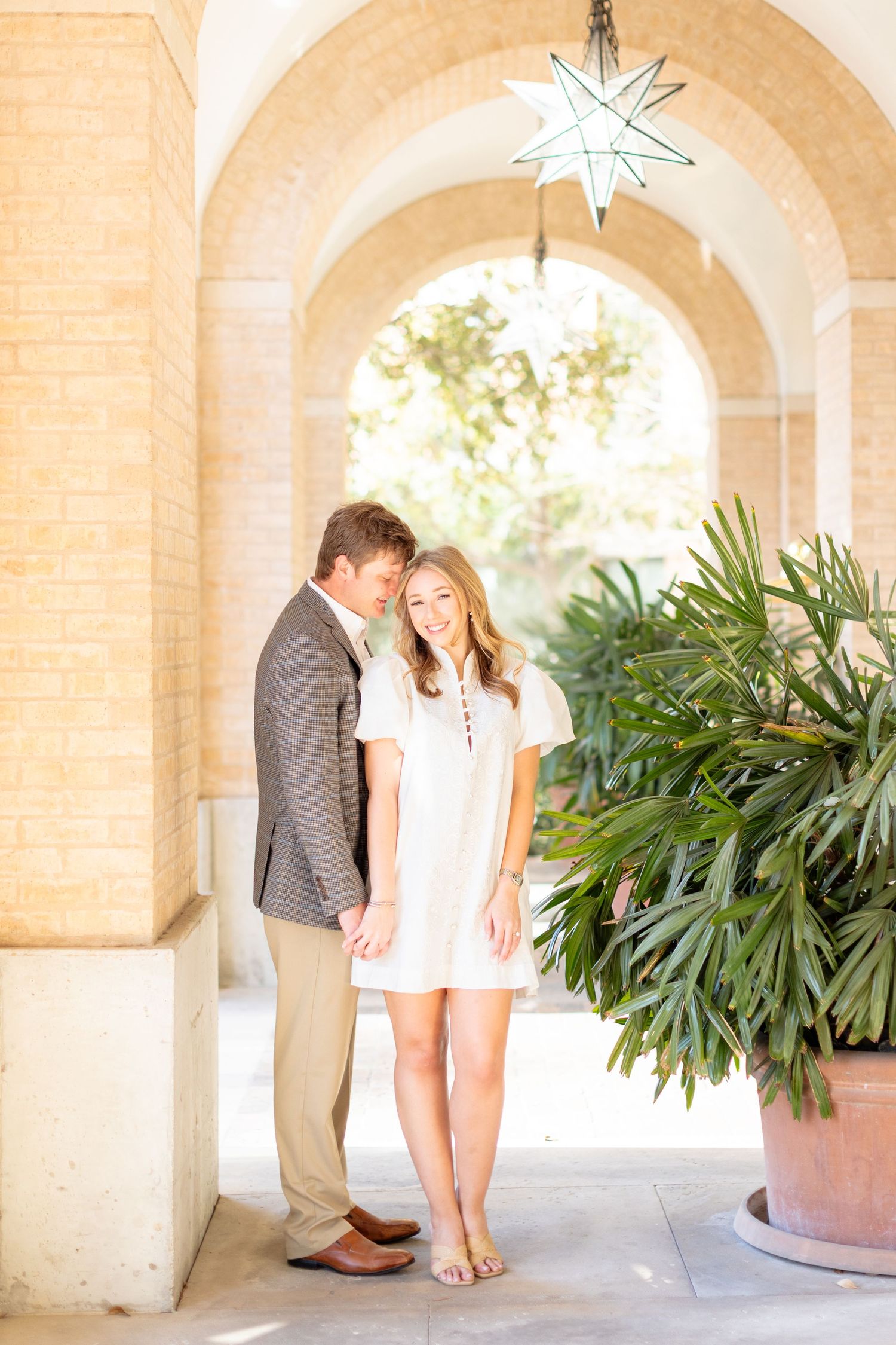 Romantic couple poses under arched walkway with hanging star lantern.
