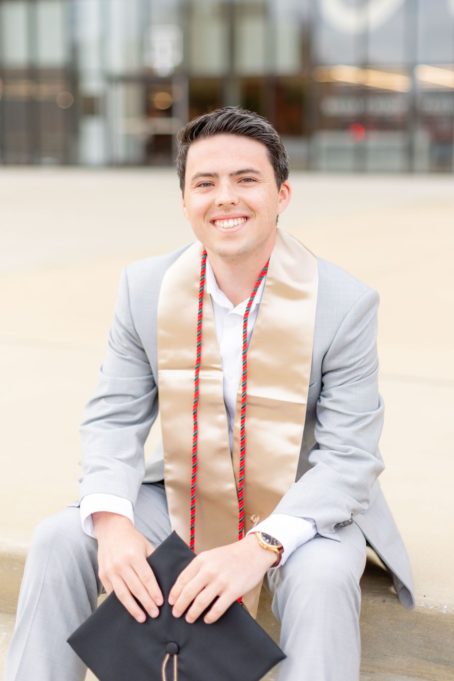 Professional wearing a light gray suit and red tie sits casually on outdoor steps in a series of candid poses.