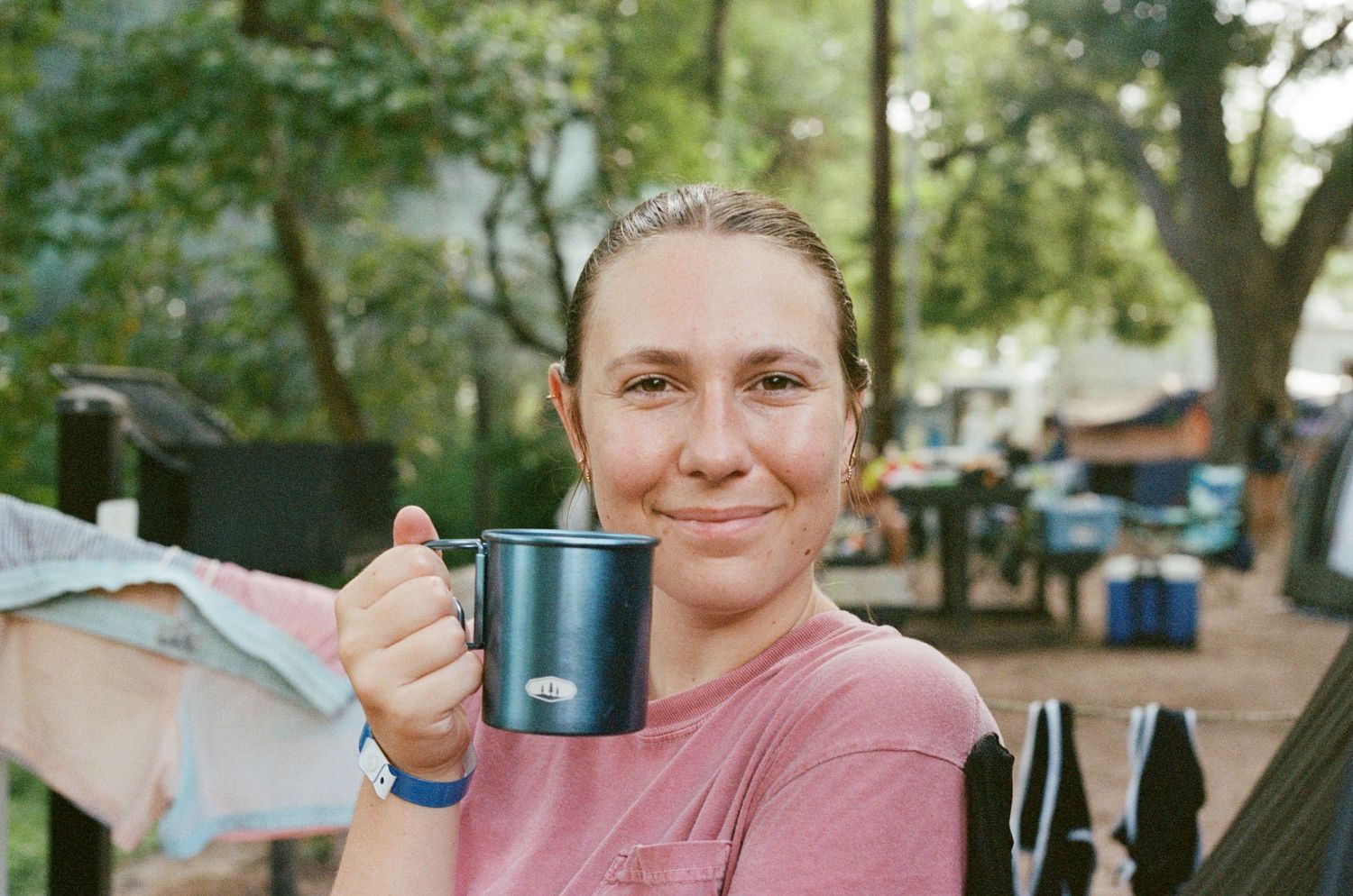 Someone holding a blue coffee mug while camping outdoors.