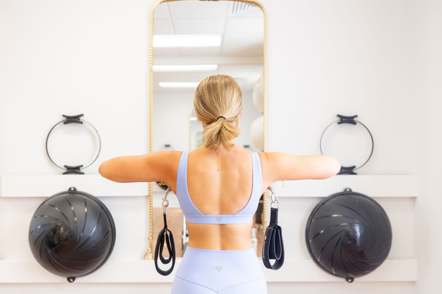View of a fitness studio with medicine balls and mirrors mounted on a white wall.
