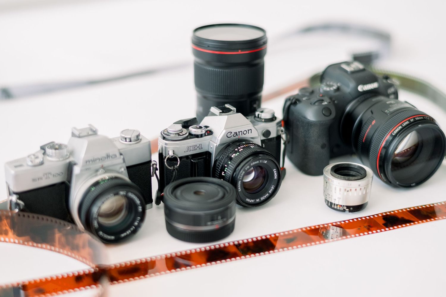 Collection of vintage and modern cameras with lenses displayed on white surface.