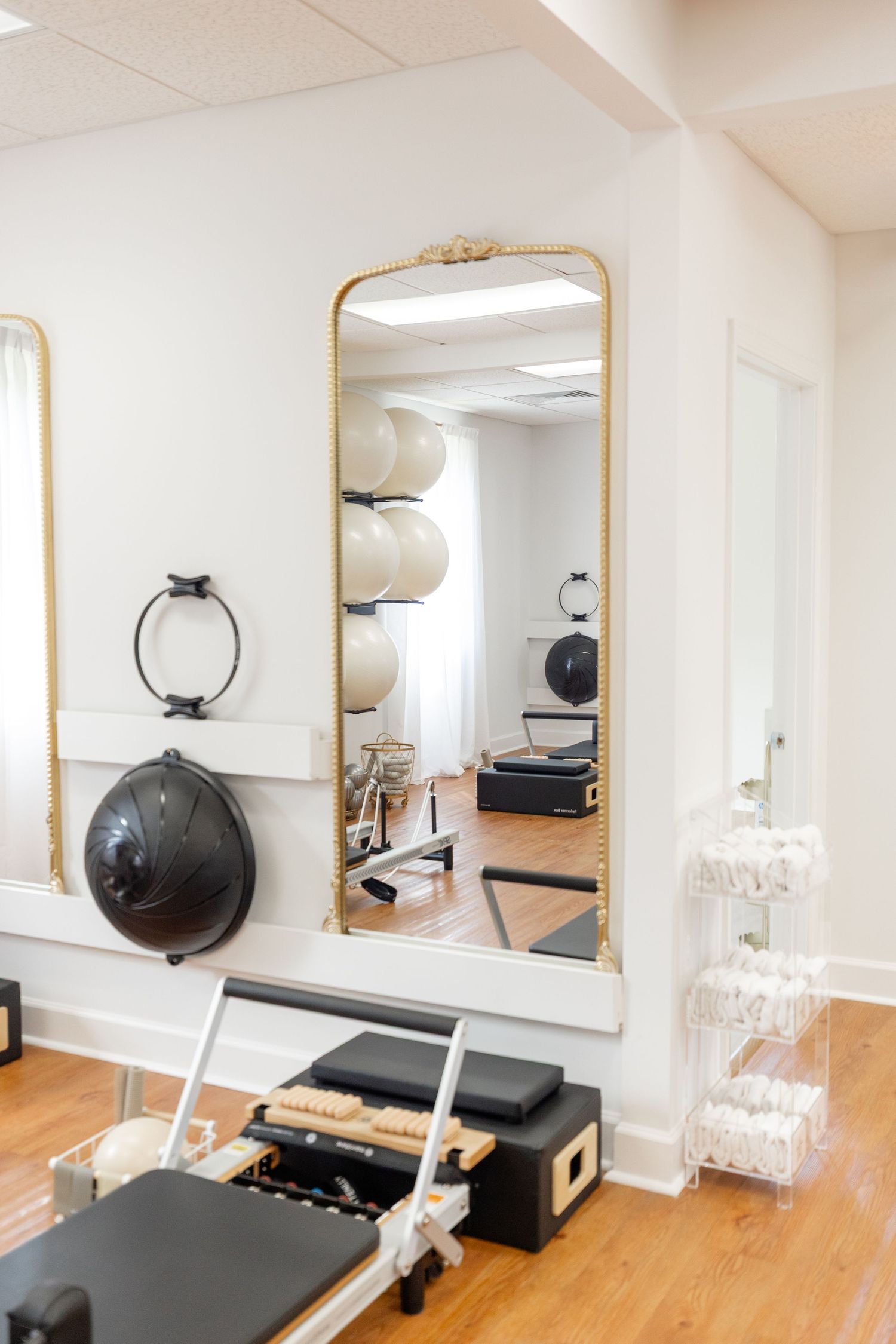 Clean fitness studio interior with gold-framed mirror and exercise equipment.