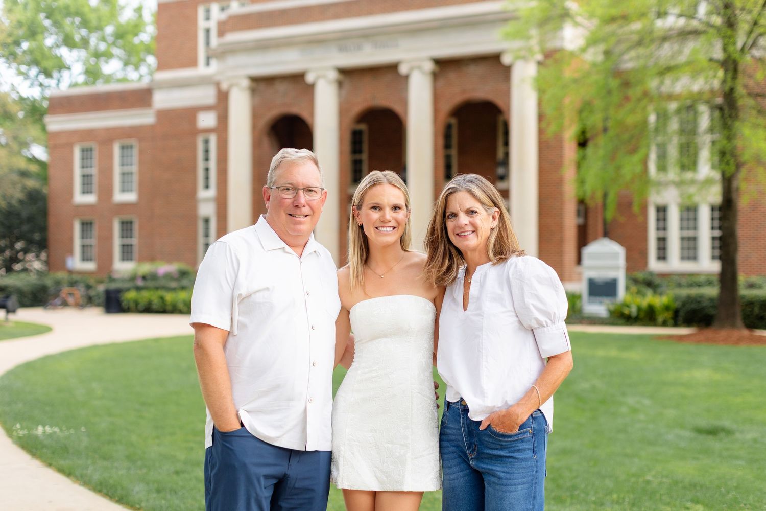 A series of outdoor family portraits taken in front of a brick building with columns on a sunny day.
