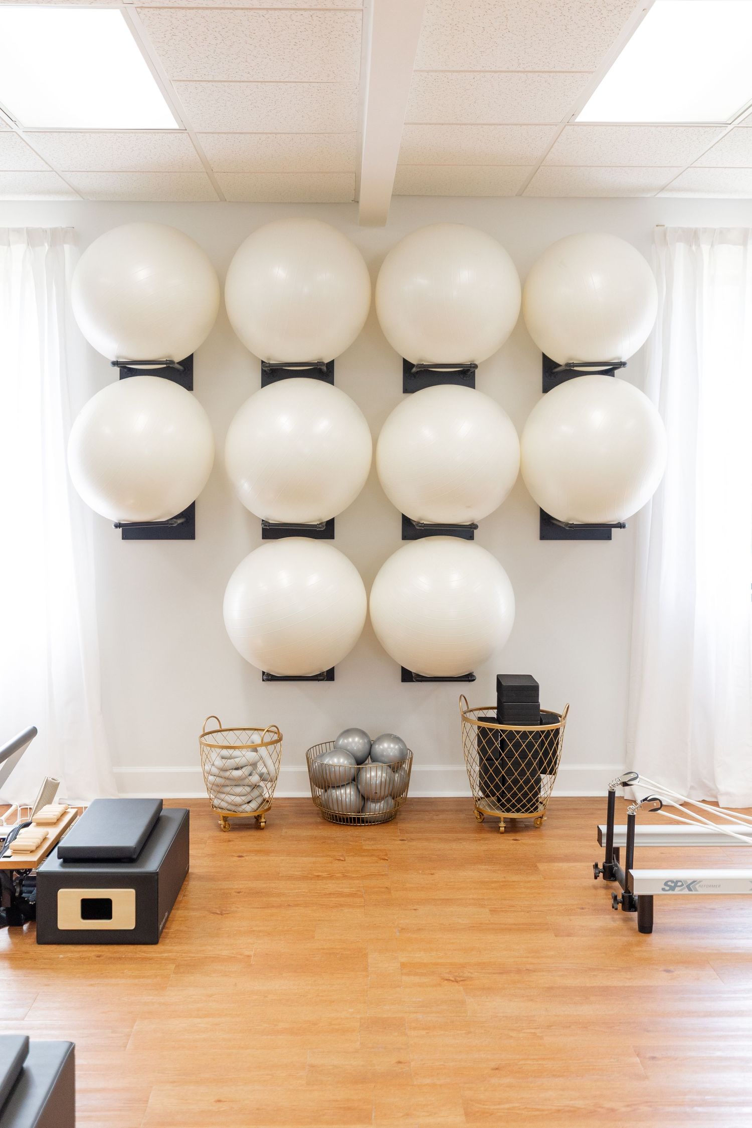 Clean pilates studio with wall-mounted exercise balls and fitness equipment.