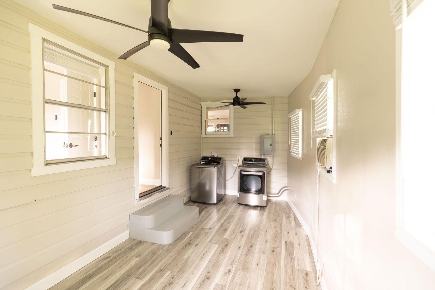 Narrow utility room with washer and dryer, wood floors, and a ceiling fan.