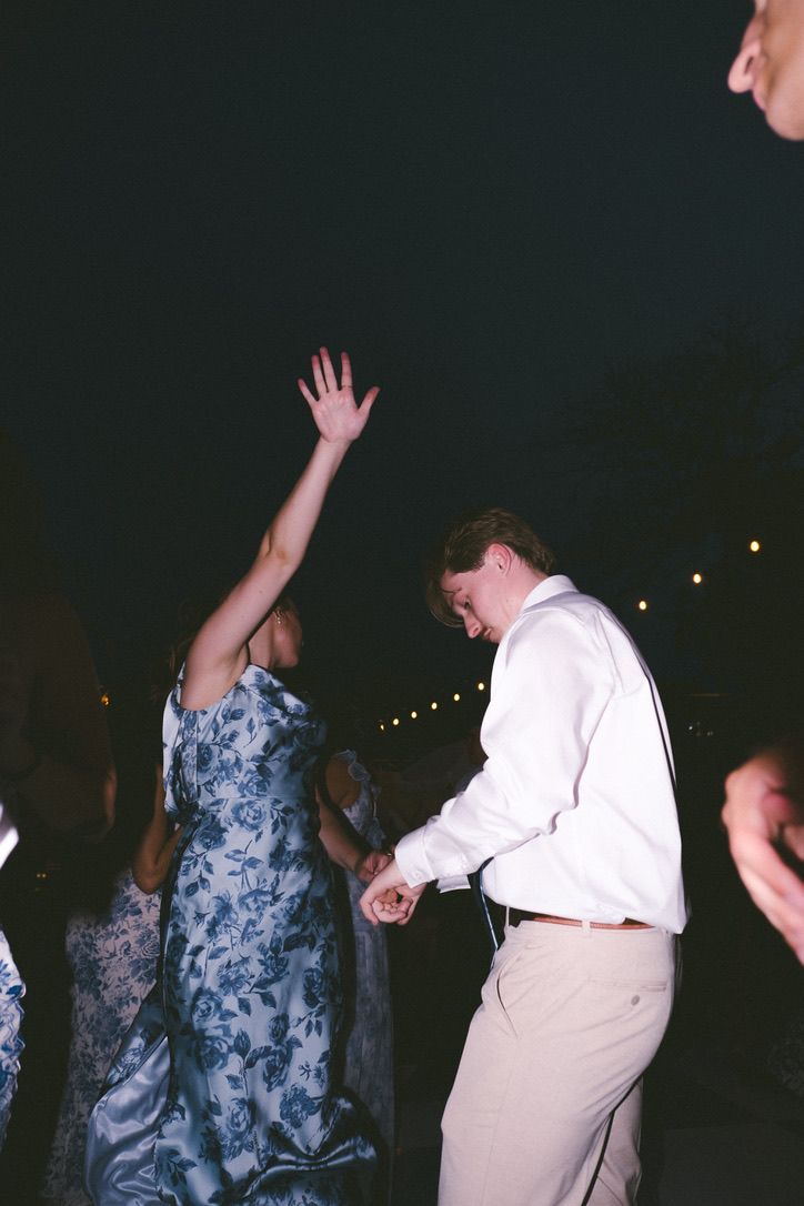 People dancing at a nighttime party with string lights in the background.