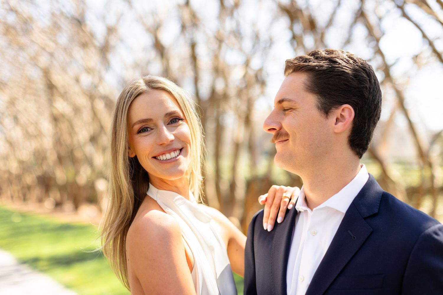 A couple shares a joyful moment together while walking outdoors in a natural setting during golden hour.