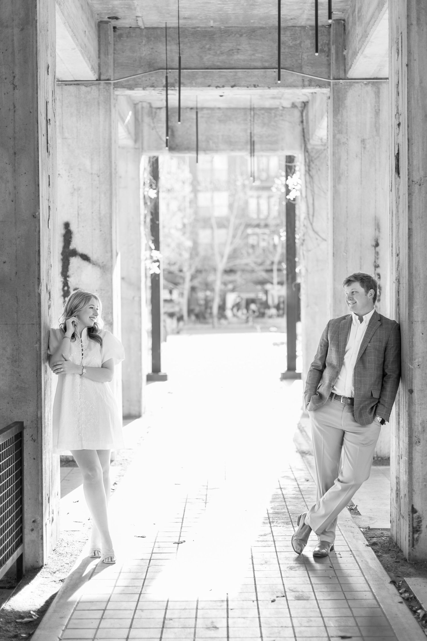 A black and white photo series showing a couple posing in an industrial concrete hallway with columns.