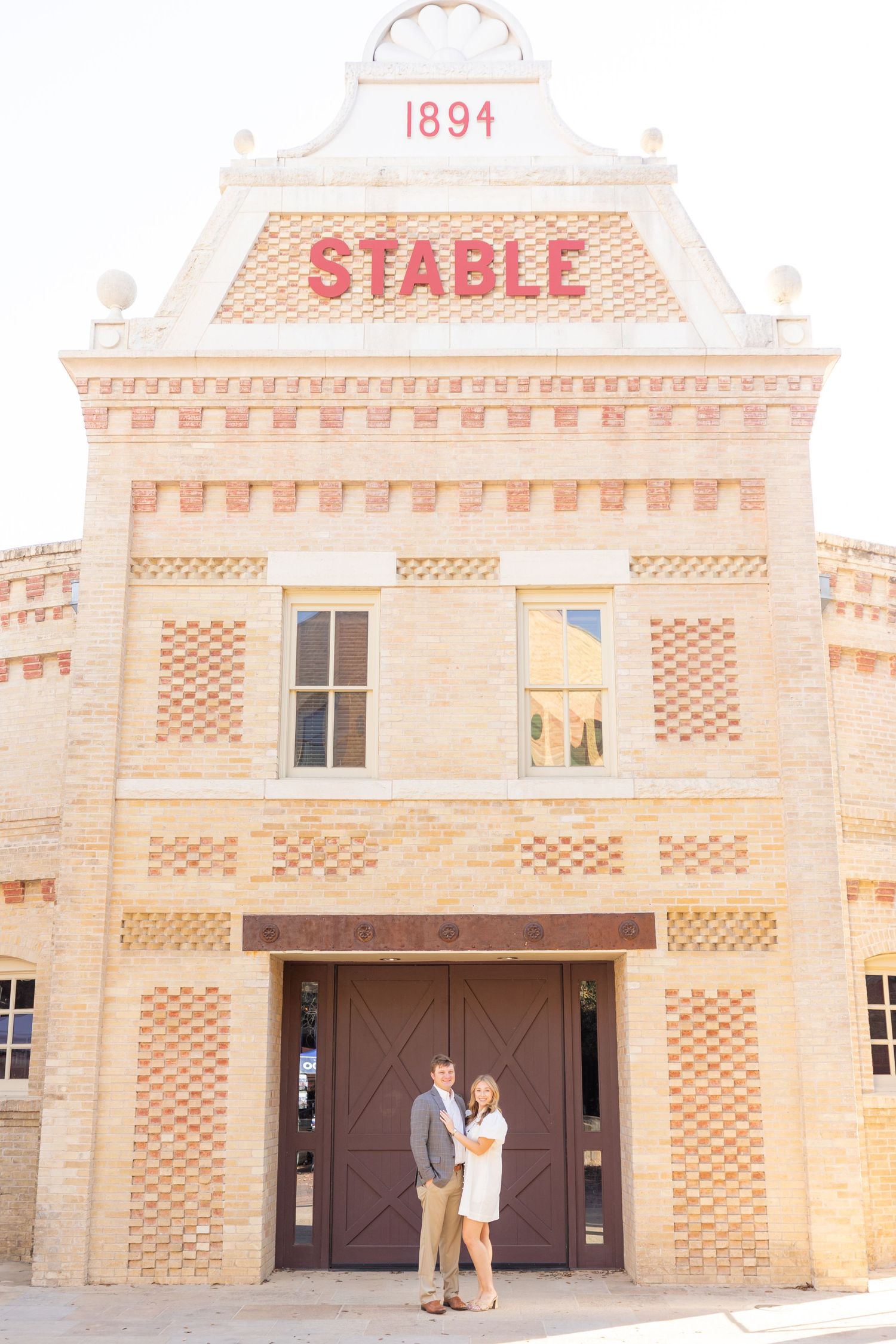 Historic 1894 stable building exterior with ornate brick patterns and wooden doors in warm beige tones.