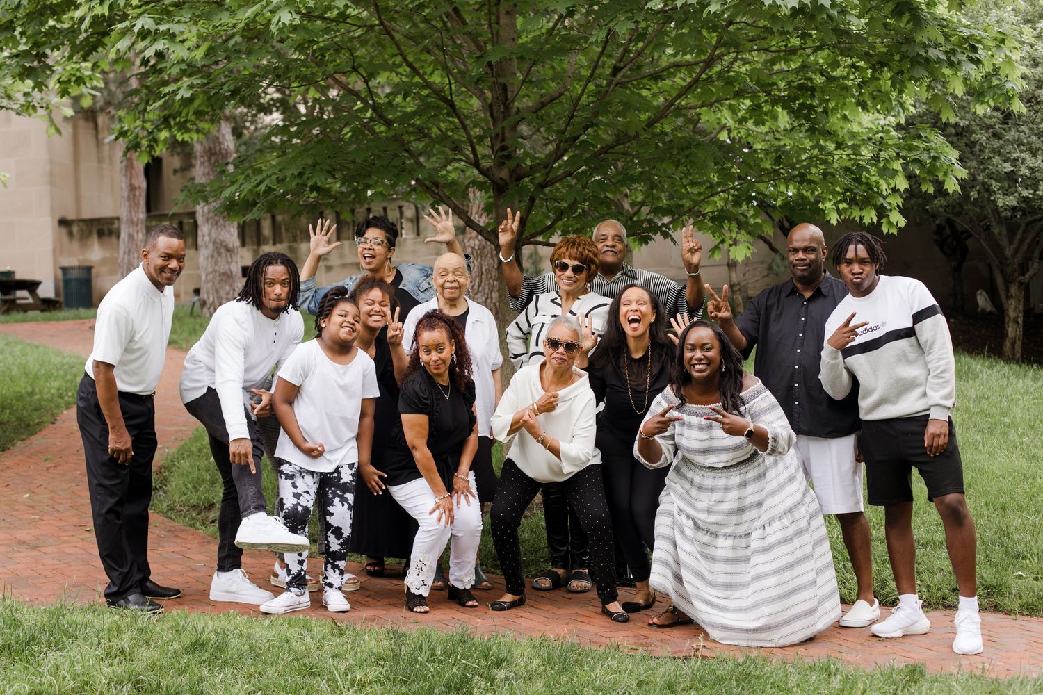 A group of people sitting and standing together for photos in a park on a sunny day.