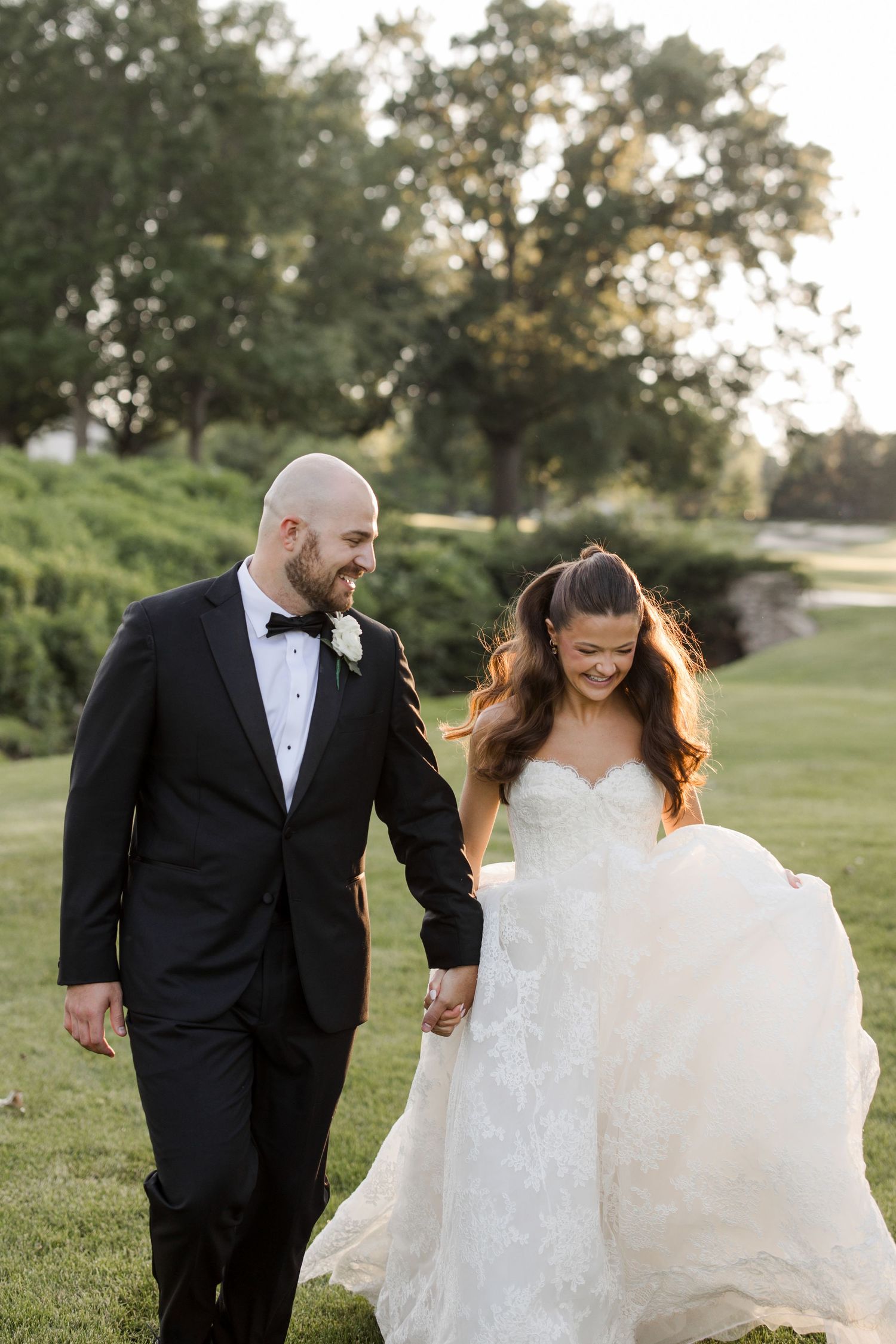 A couple shares a joyful candid moment outdoors on their wedding day.