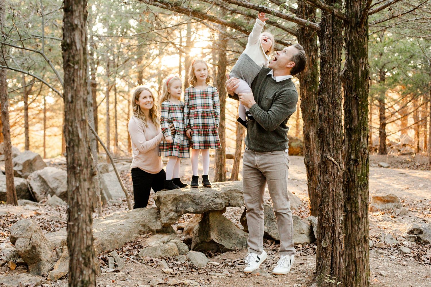 Playful family moment captured in a forest during golden hour.