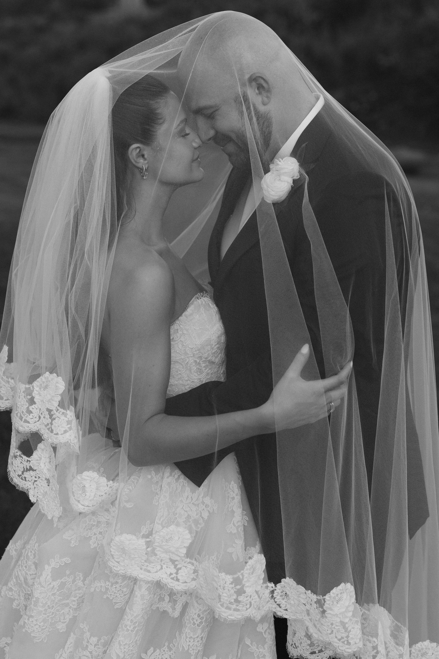 A romantic black and white wedding series shows tender moments shared under a flowing bridal veil.