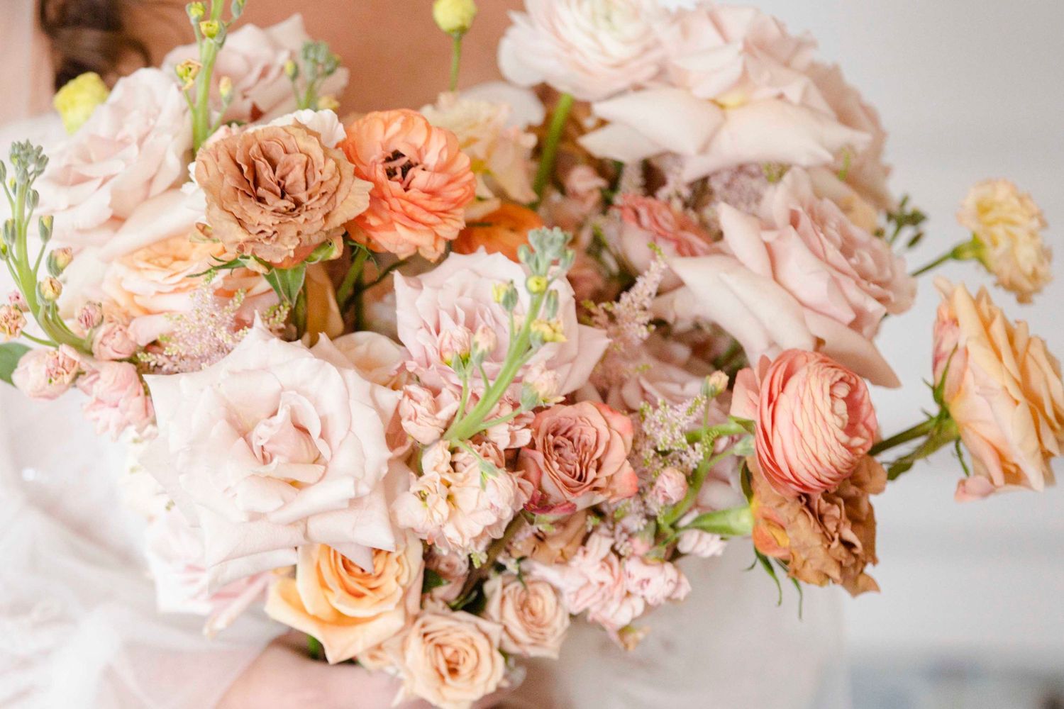 Artful arrangement of coral and blush garden roses in soft natural light. Johnson County Wedding Photographer