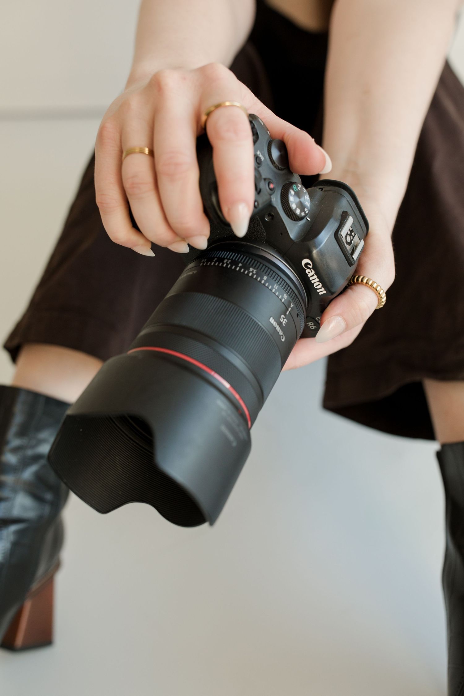 Close-up of hands holding professional camera with lens against white background. Wedding and Portrait Photographer Hannah Taylor.