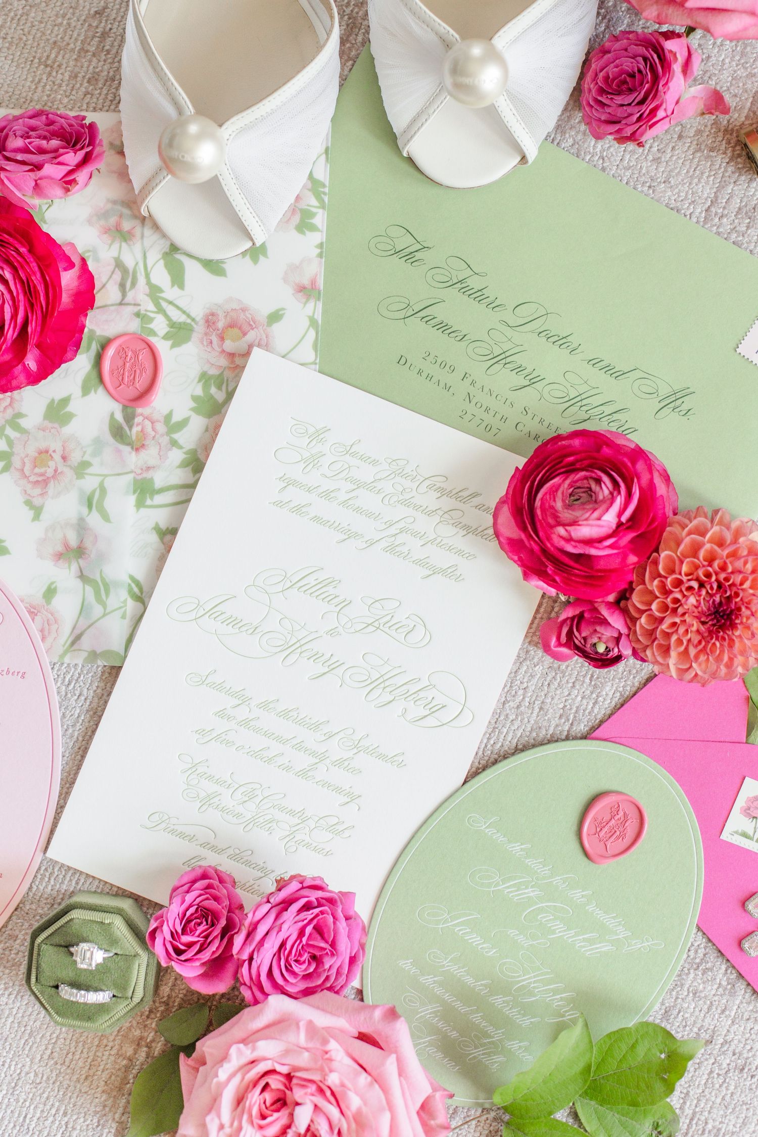 Wedding invitation suite with white bridal shoes, pink roses, and mint green stationery on light fabric background.