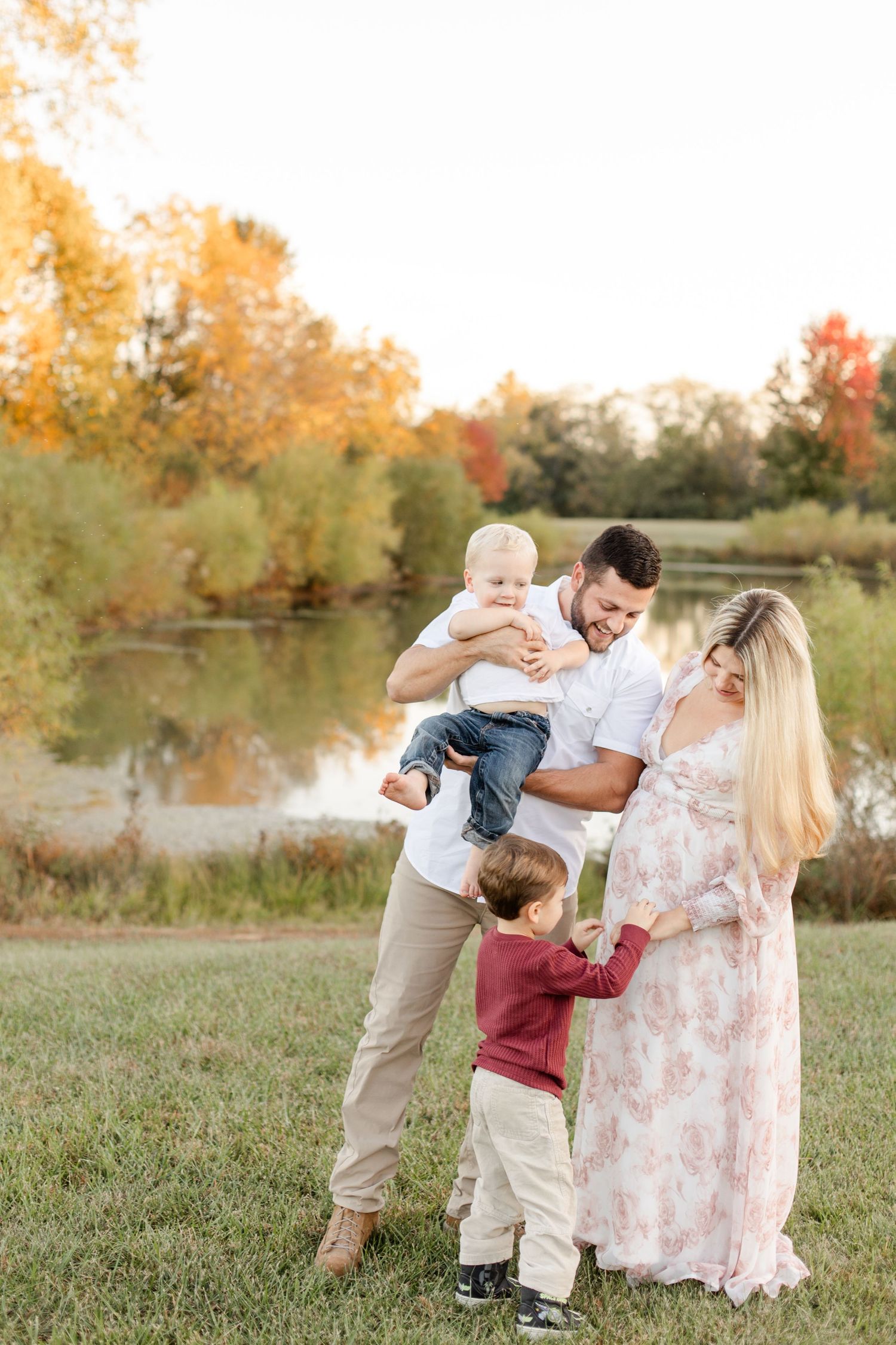 Family portrait in autumn setting near pond with golden foliage. Missouri family photography.