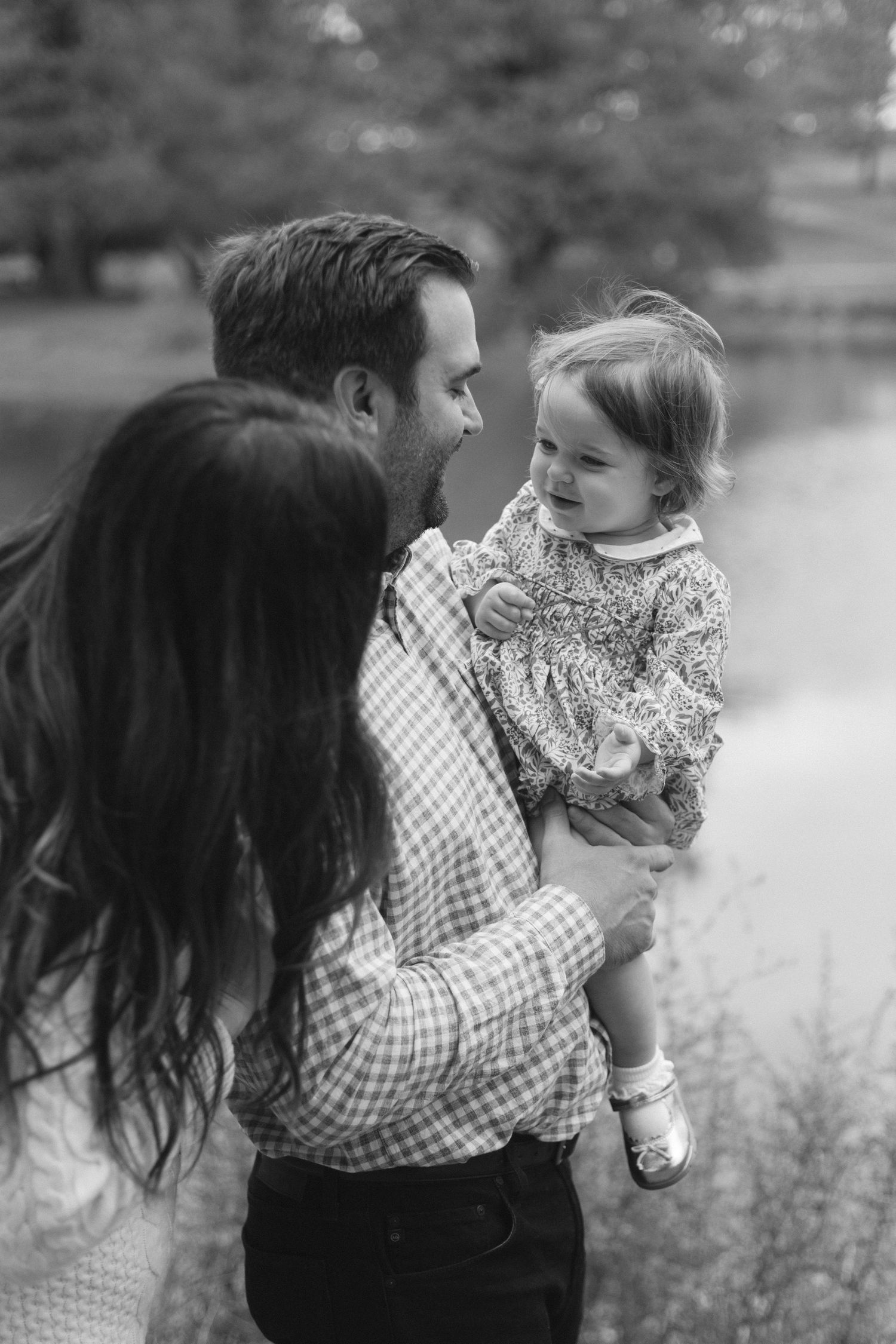 Black and white candid family portrait capturing an intimate moment outdoors.