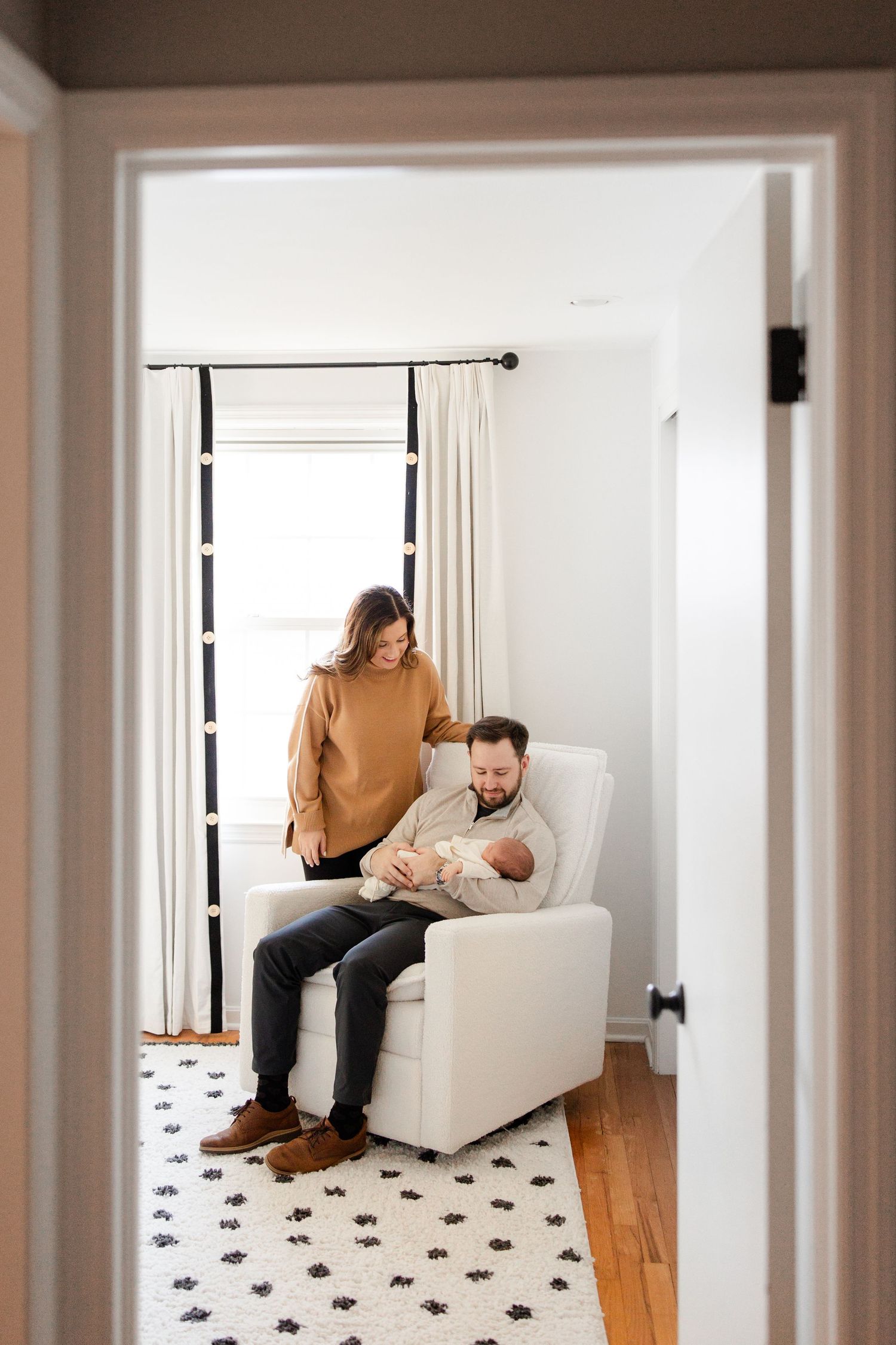 Intimate indoor portrait of family moment in white modern nursery setting.