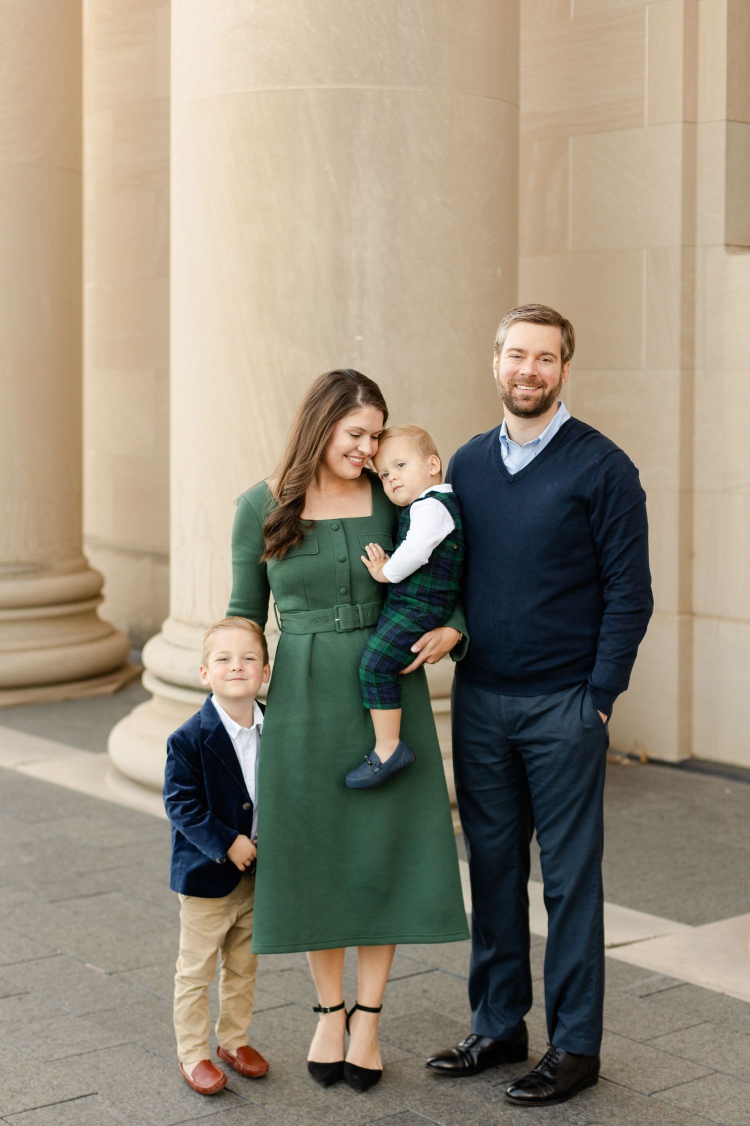 Family portrait in formal attire standing against classic stone columns at Nelson Atkins Museum of Art in Kansas City.