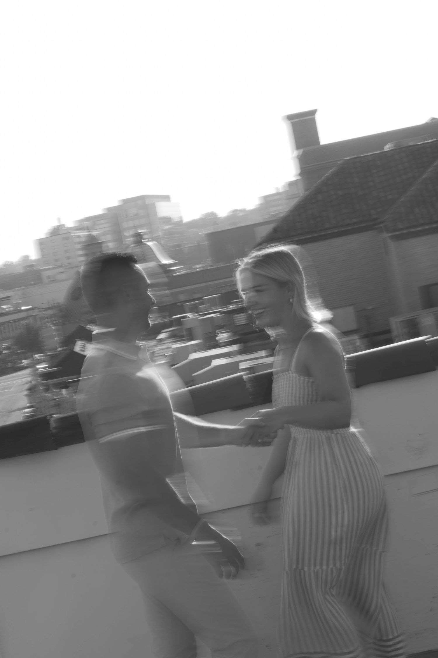 Black and white motion blur photo of two people dancing on a rooftop.