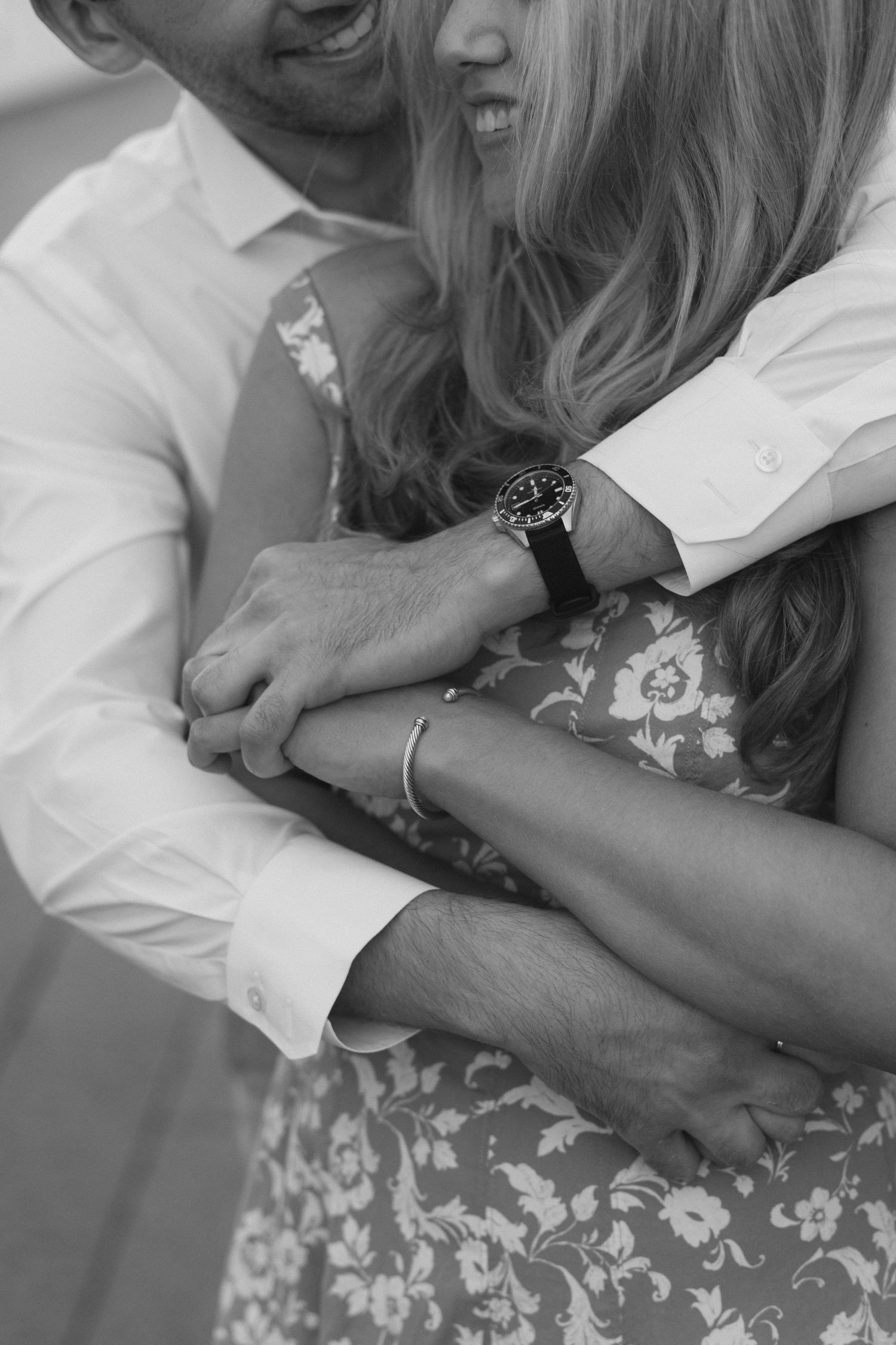 Intimate black and white photo of a couple embracing, showing jewelry and formal attire details.