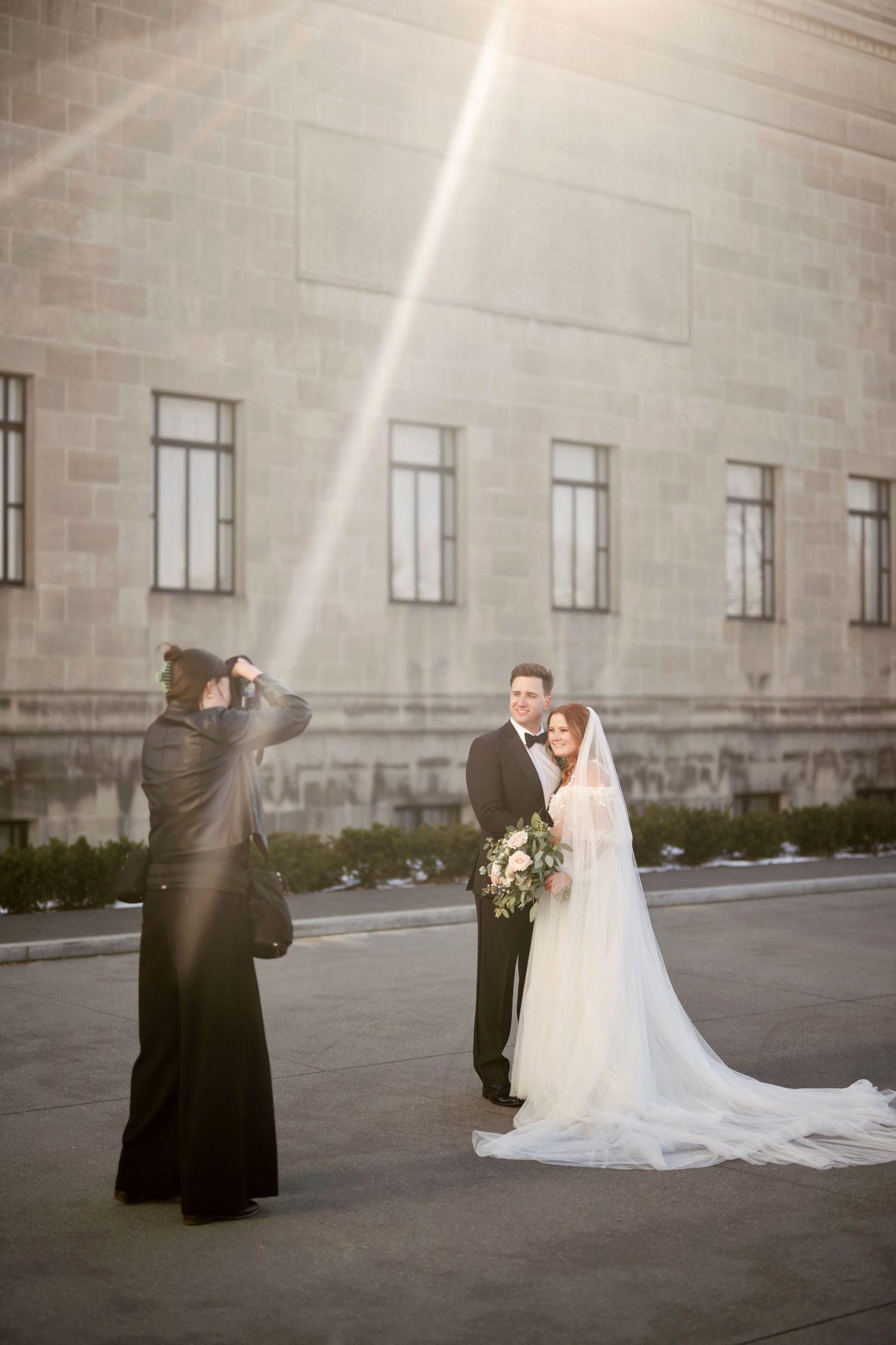 Behind the scenes of wedding photography with photographer Hannah Rogg Taylor capturing couple against stone building.