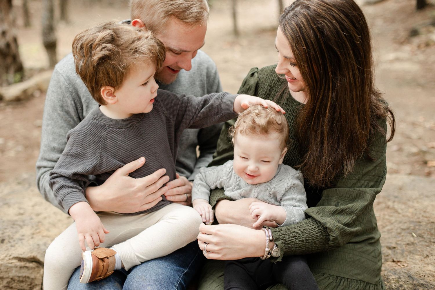 Family of four sharing intimate moment together during outdoor photo session.