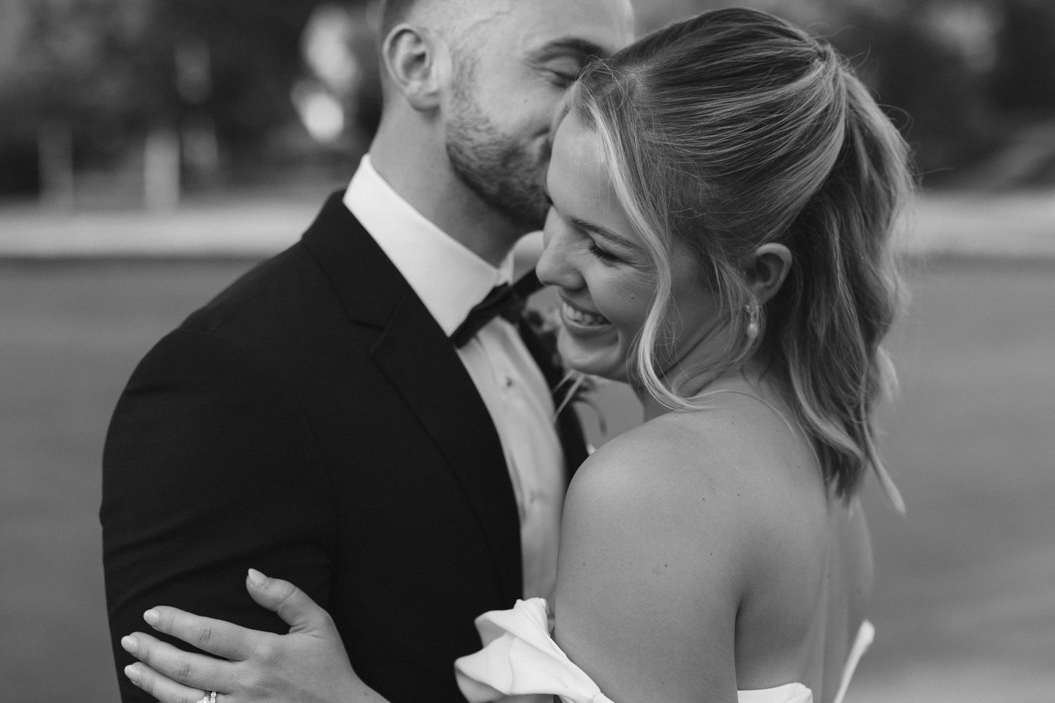 Black and white candid wedding photograph showing intimate moment between bride and groom dancing together.