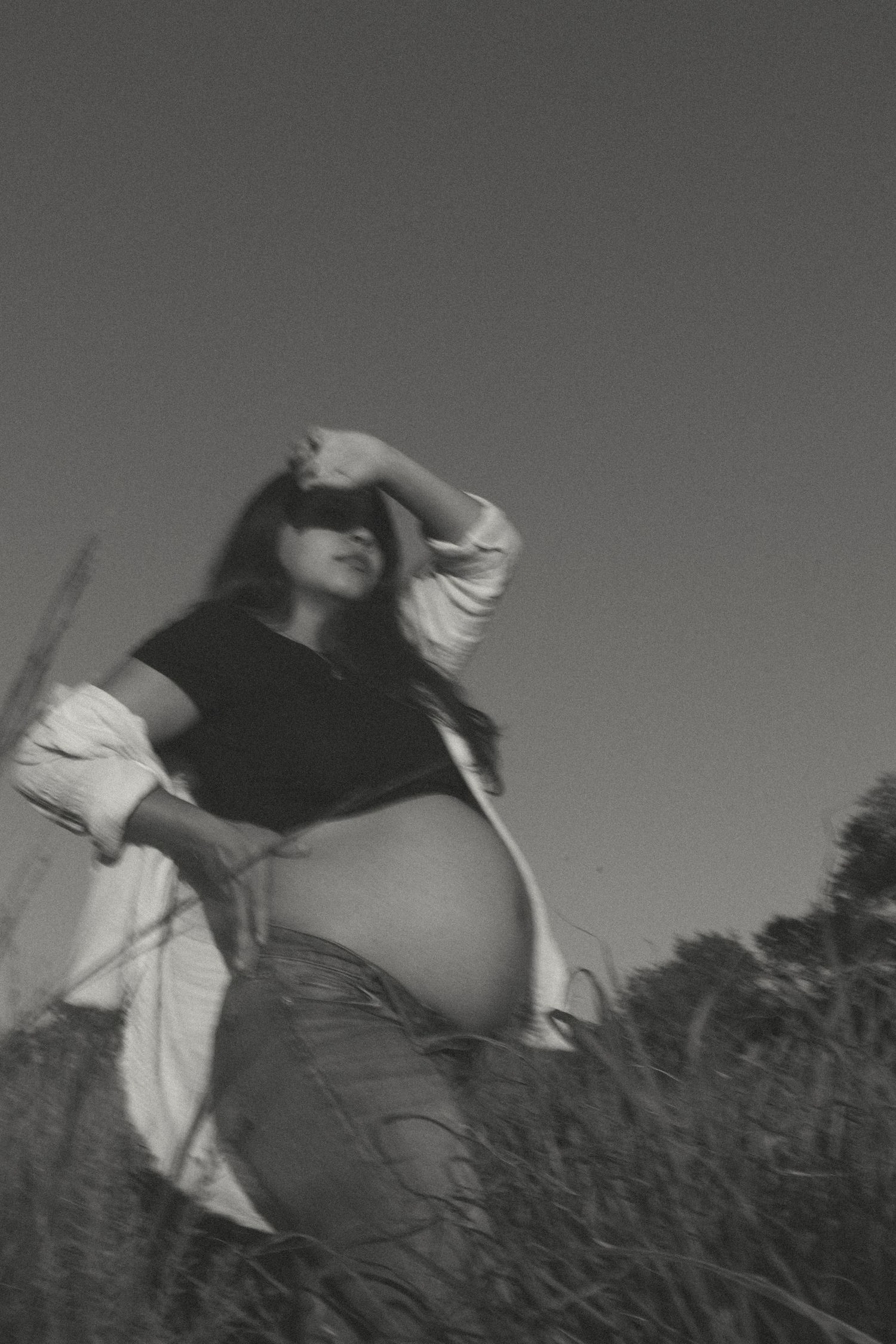 Silhouette of an expectant mother standing in a field at sunset. KC Maternity Photos by Hannah Taylor.