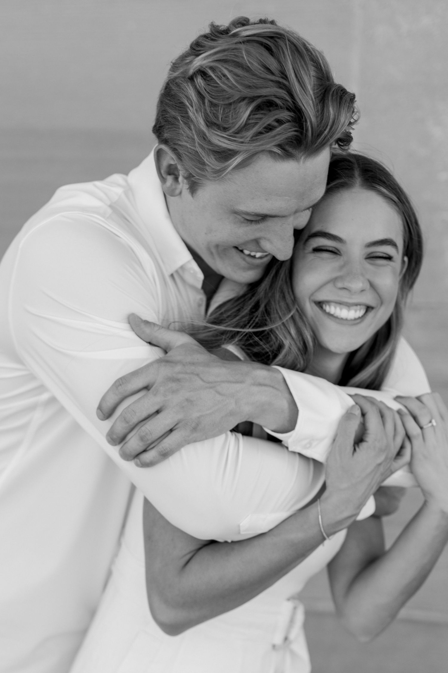 Joyful black and white portrait of a couple embracing and laughing together. Kansas City engagement photos.