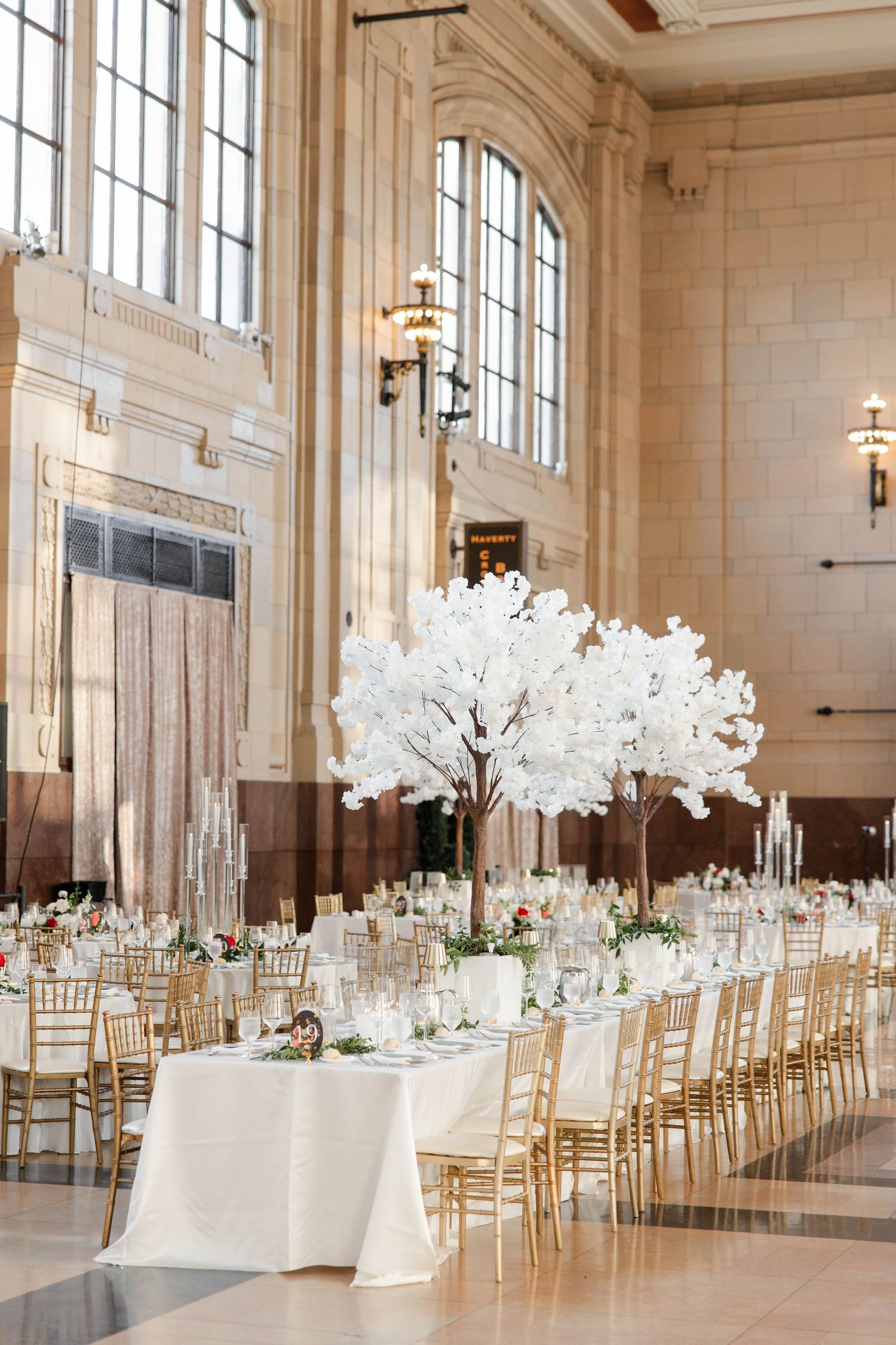 Grand ballroom wedding reception with white cherry blossom tree centerpiece and gold chairs at Union Station in Kansas City.