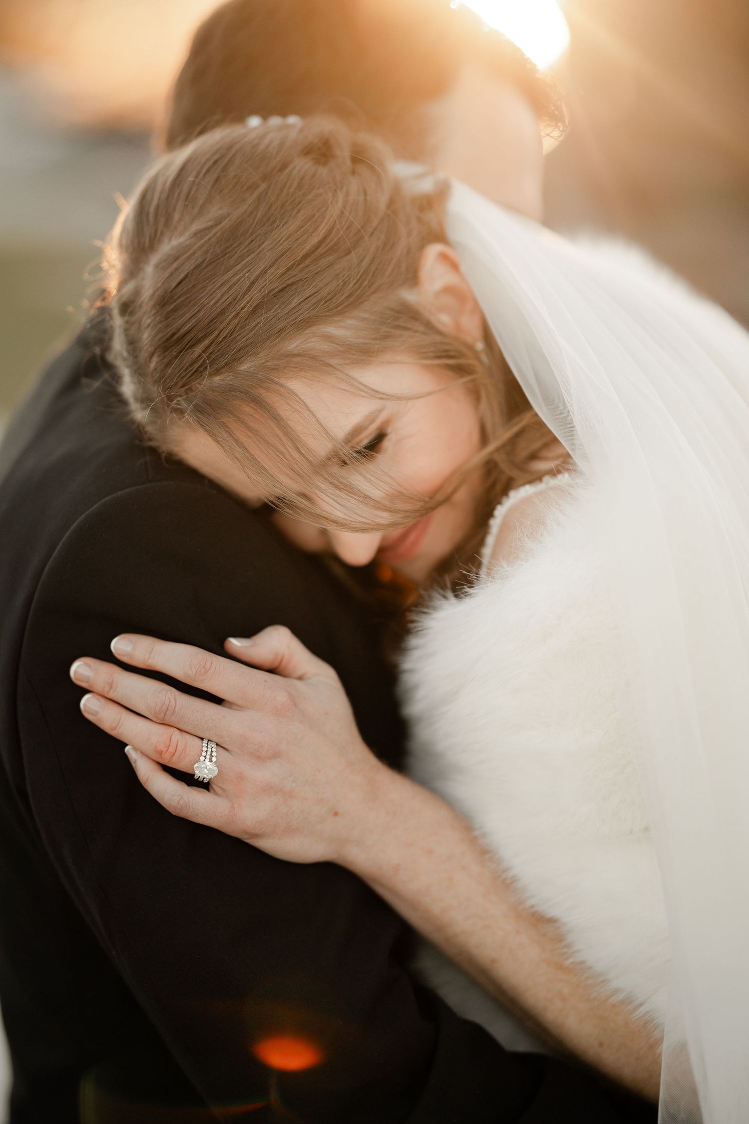 Intimate sunset moment between newlyweds with bride's engagement ring visible.