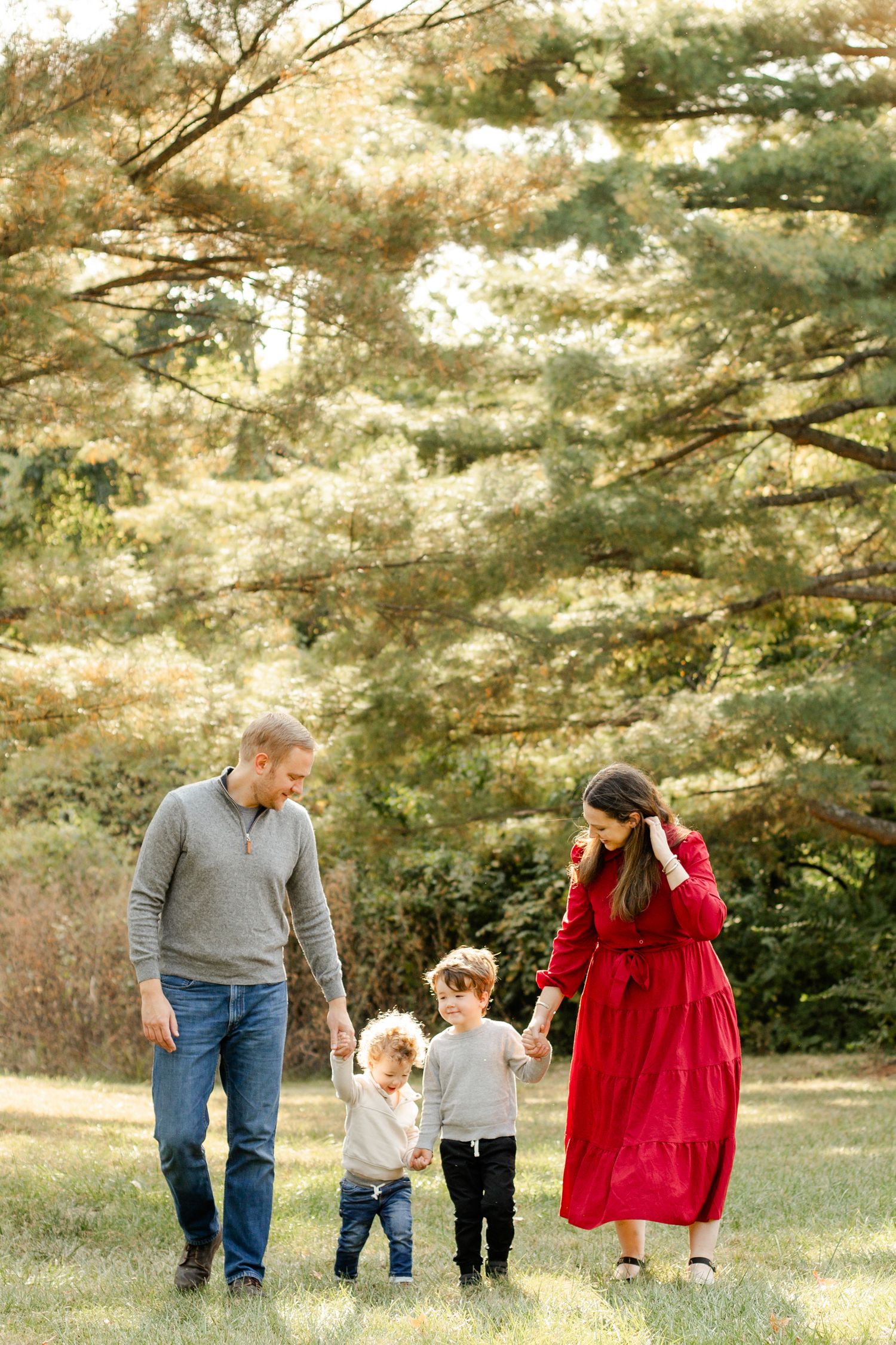 Family walking together on a sunny day in a wooded area.