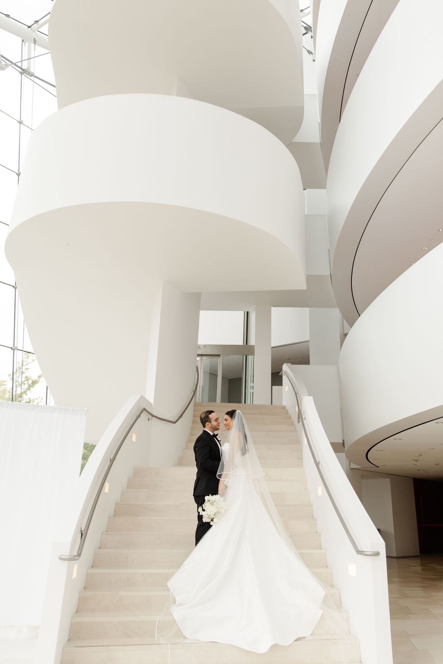 Modern white architectural interior with curved arches and a sweeping staircase.
