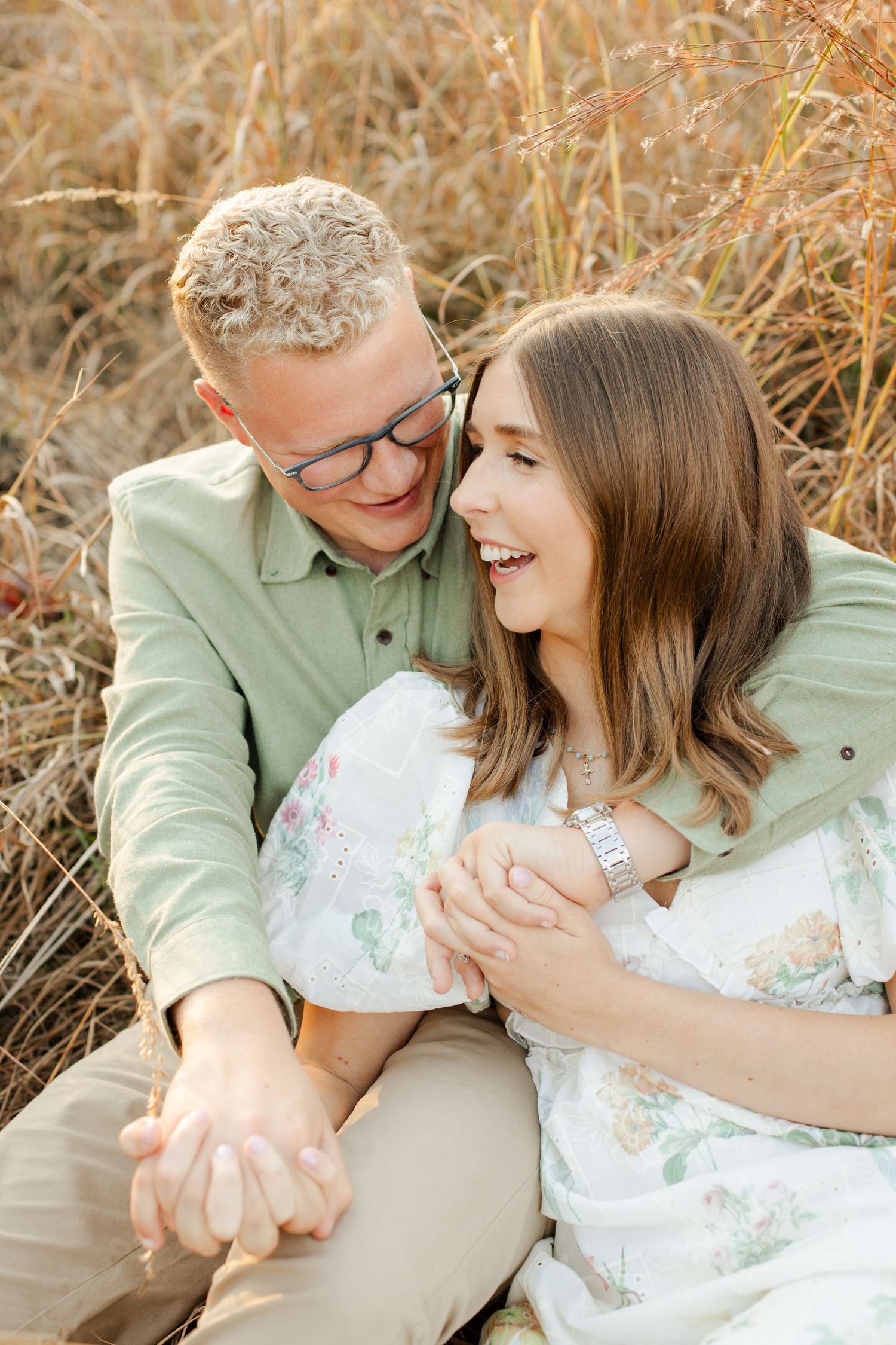 Joyful couple sharing intimate moment while sitting in tall autumn grass, photographer Hannah Rogg Taylor