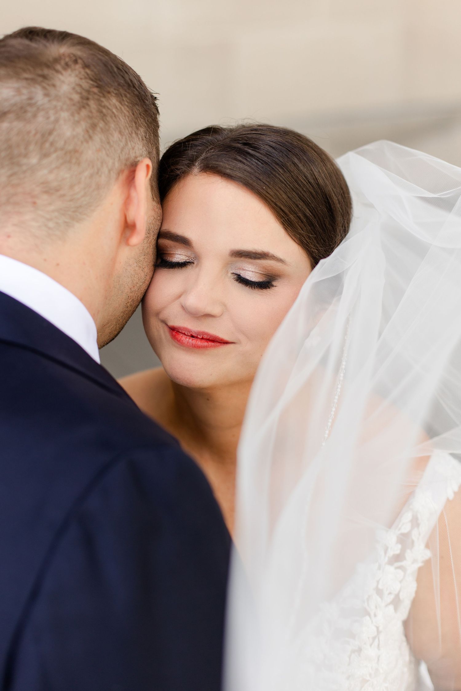 Intimate wedding portrait capturing a tender moment between newlyweds with flowing veil and formal attire.