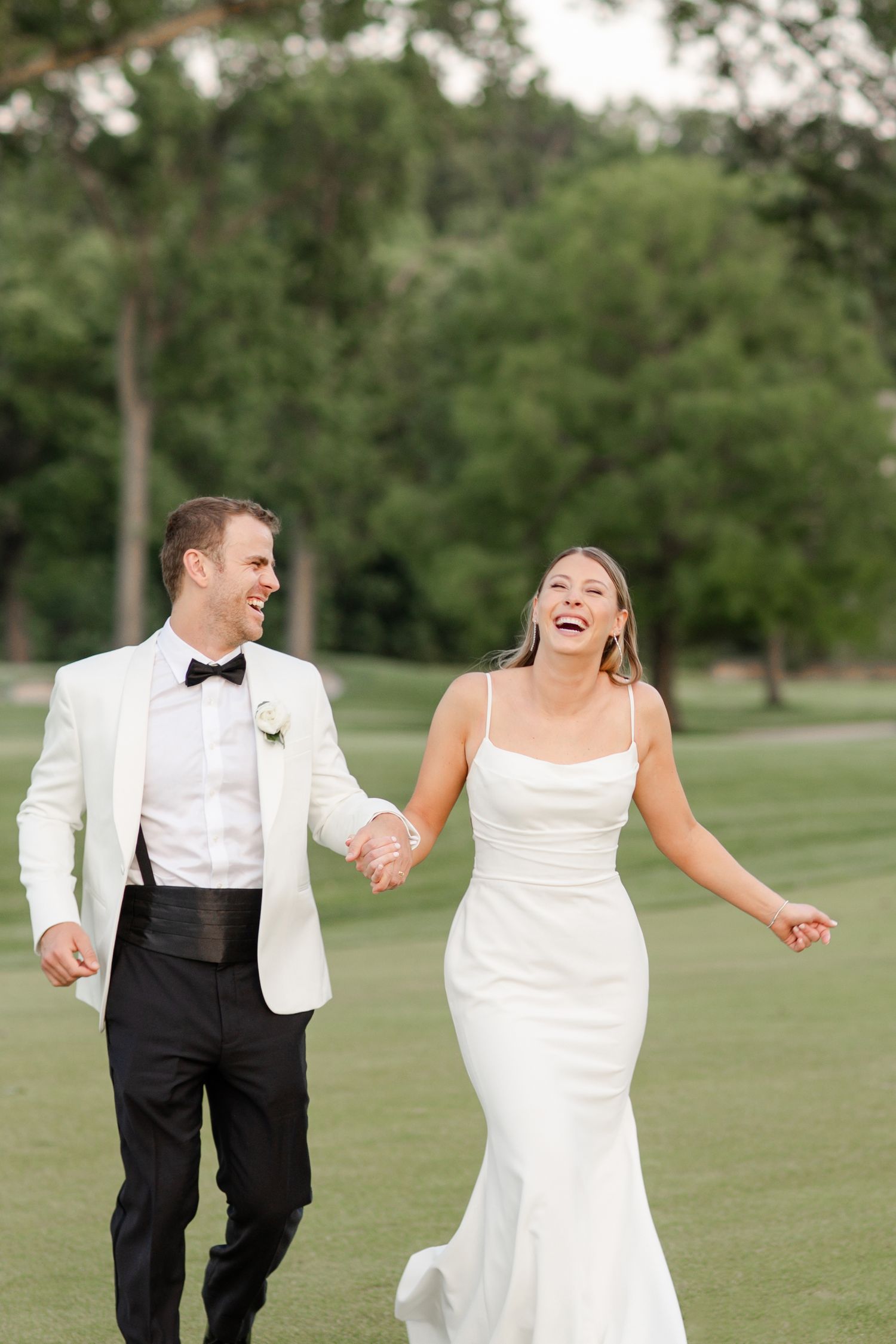 Newlyweds sharing a carefree moment while running together on a golf course at Mission Hills Country Club Wedding in Kansas City.