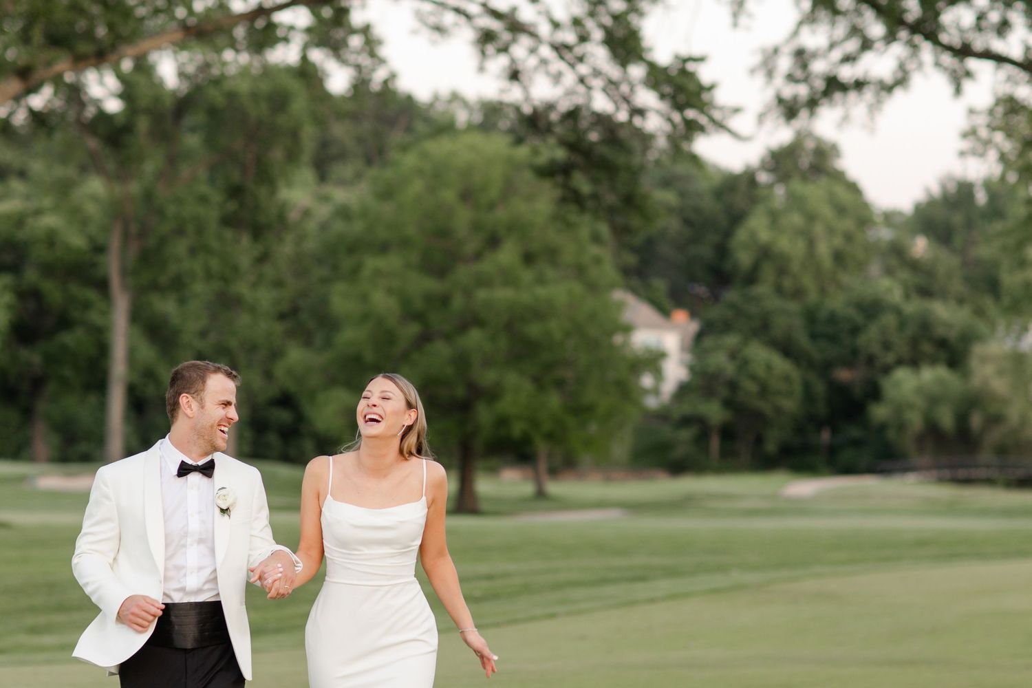 A couple shares a joyful moment while walking on a scenic golf course.
