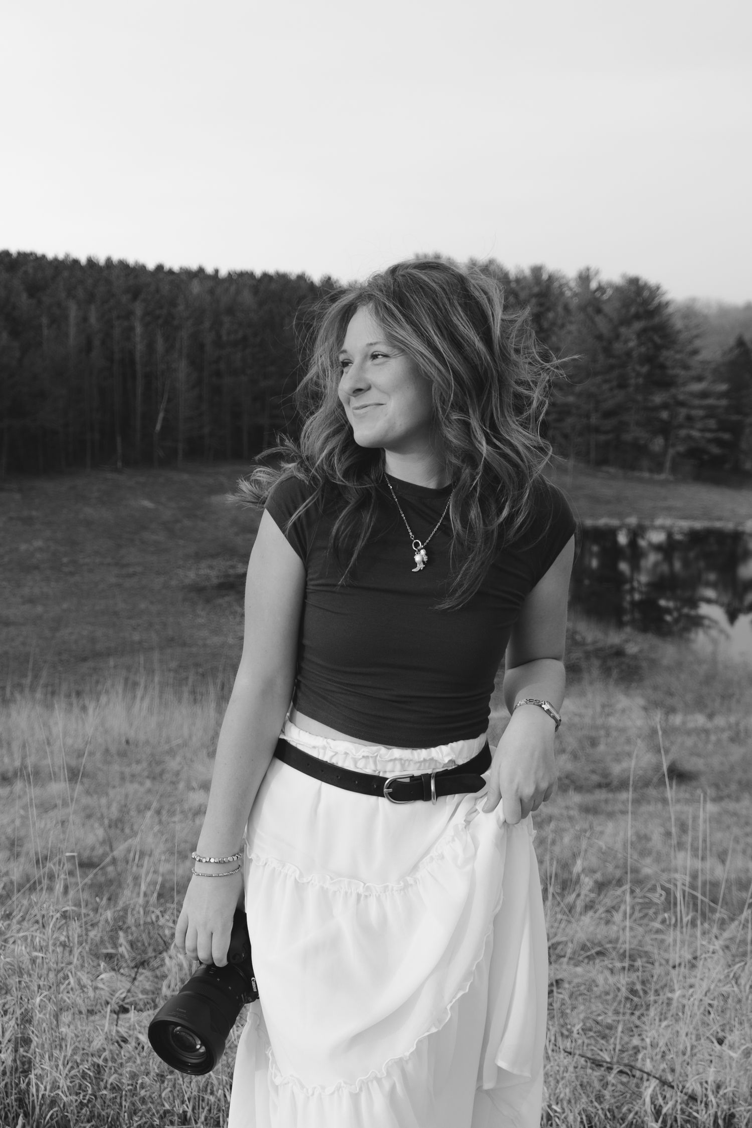 Black and white portrait of elizabethrophoto standing in an open field. Captures candid joy and natural light in a timeless style.