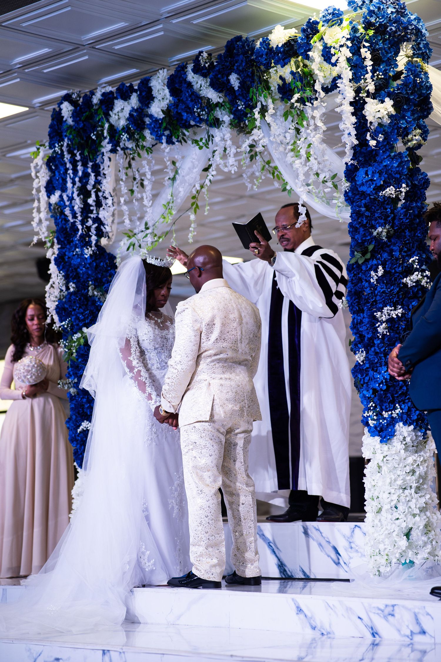 Las Vegas bride and groom join hands as pastor pronounces marriage under floral stage decor.