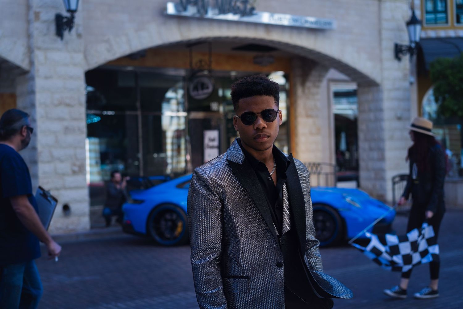 Man in suit jacket posing in front of race car in Tivoli Village.